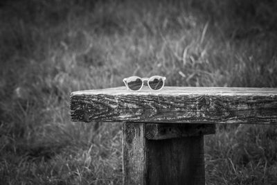 Close-up of sunglasses on wooden bench 