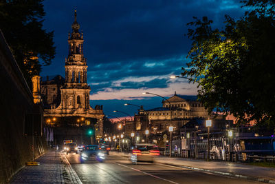 Cars on road by illuminated buildings in city at night