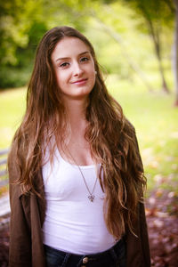 Portrait of smiling young woman standing at park
