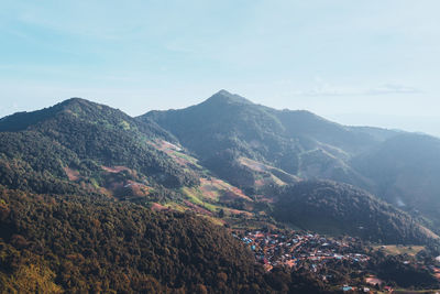 Aerial view of townscape by mountains against sky