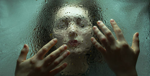 Close-up of woman seen through wet glass