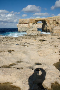 Rock formation on beach against sky