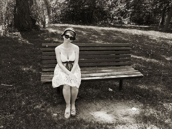 Full length portrait of woman standing on bench in park
