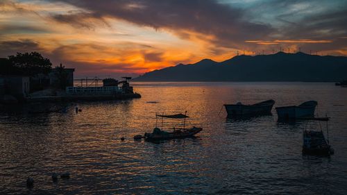 Fishing boat in sea against sky during sunset