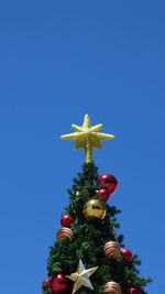 Low angle view of christmas tree against clear blue sky