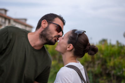 Portrait of young couple kissing against sky