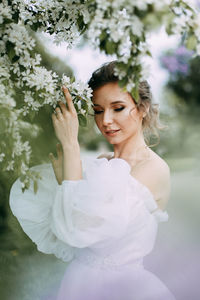 A beautiful delicate elegant woman bride in a wedding dress walks alone in a spring outdoor park