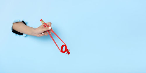 Close-up of hand holding red umbrella against clear sky