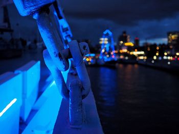 Close-up of hand against illuminated blue water