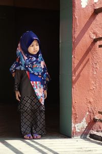 Hijab -wearing children stare outside the house
