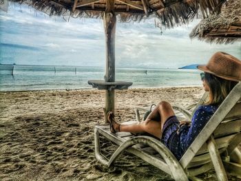 Rear view of man sitting on chair at beach