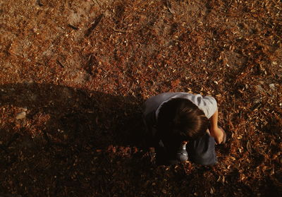 Directly above shot of boy holding microphone while crouching on field