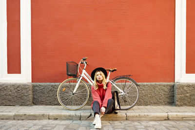 Full length portrait of boy on bicycle against wall