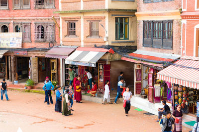 People walking on street amidst buildings in city