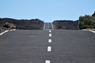 Road by trees against clear sky