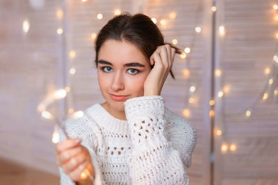 Portrait of young woman holding illuminated lighting equipment