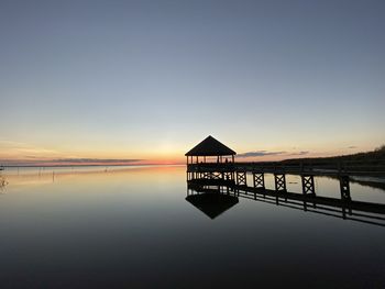 Pier over lake against sky during sunset