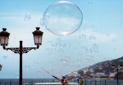 Street light and soap bubbles on promenade against sky