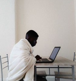 Side view of man using mobile phone while sitting on table