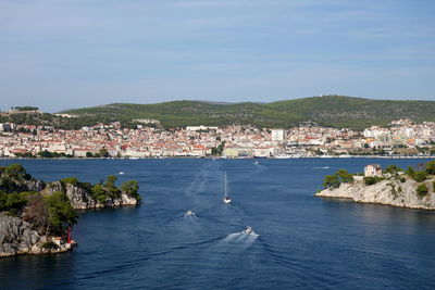 Scenic view of sea by townscape against sky