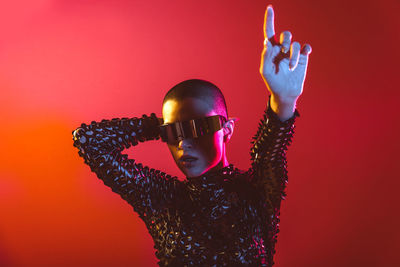 Woman wearing eyeglasses standing against red background