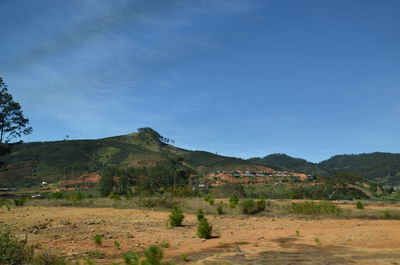 Scenic view of landscape and mountains against blue sky