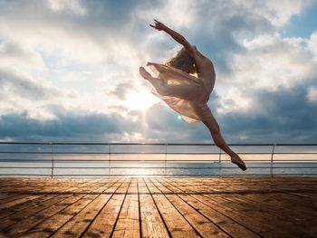 Low angle view of woman jumping on sea against sky