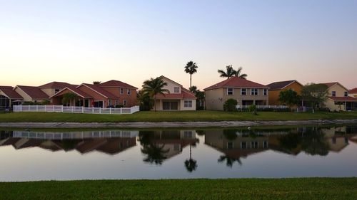 Reflection of houses in lake against clear sky