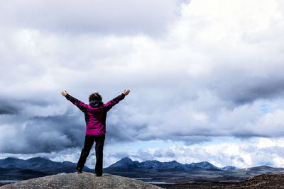 Man standing on snow covered mountain against cloudy sky