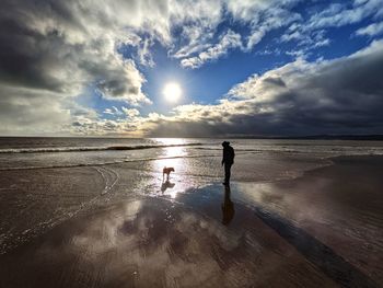 Silhouette people on beach against sky