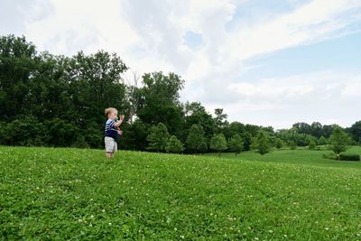 Boy on grass field against sky