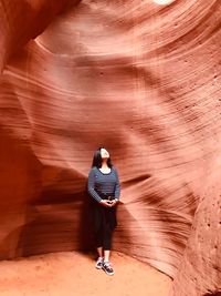 Woman standing against rock formation in cave