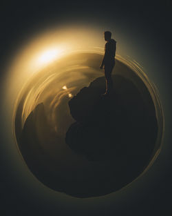 High angle view of silhouette man standing at beach during sunset