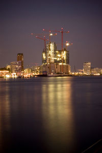 Illuminated city by river at night