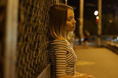 Woman standing against fence on road