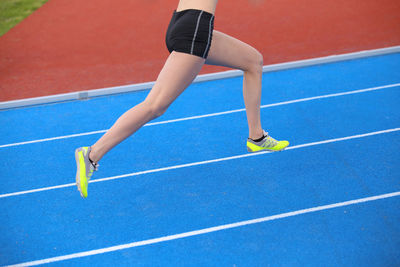 Low section of woman running on track