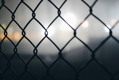 Full frame shot of chainlink fence against sky during sunset