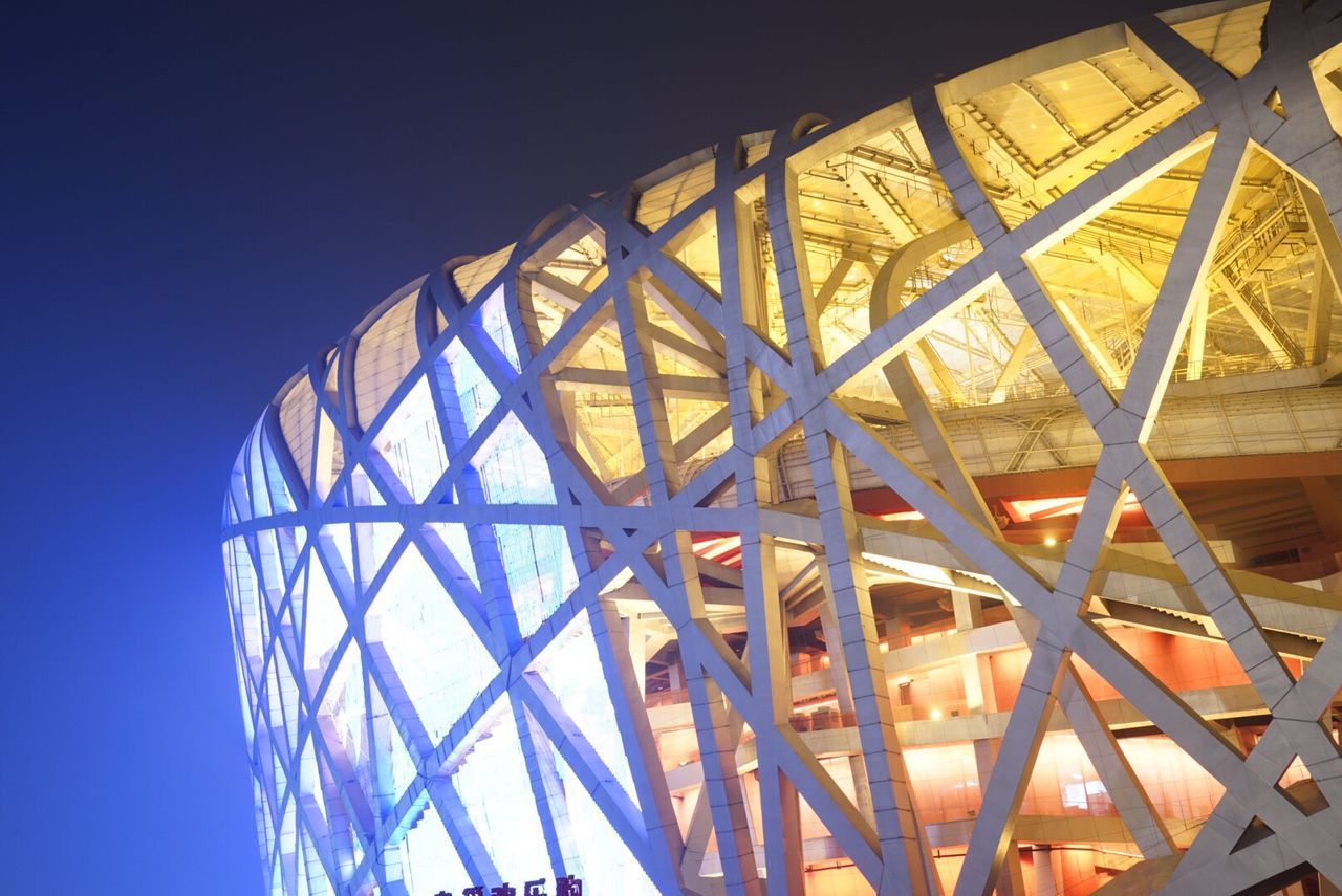 low angle view, built structure, architecture, metal, clear sky, blue, pattern, metallic, building exterior, sky, arts culture and entertainment, architectural feature, geometric shape, illuminated, no people, amusement park ride, outdoors, amusement park, modern, engineering