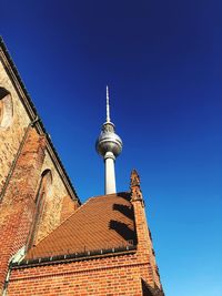 Low angle view of communications tower against blue sky