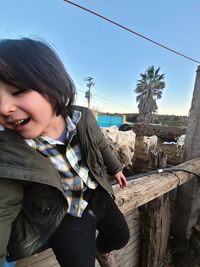 Young woman smiling while standing against sky