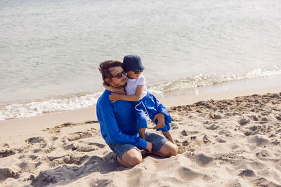 Dad and son play on the beach in summer in blue clothes while on vacation