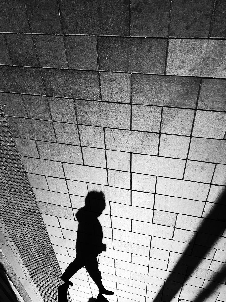 walking, architecture, real people, one person, built structure, men, side view, day, silhouette, wall - building feature, child, city, lifestyles, childhood, motion, outdoors, leisure activity, pattern, shadow, paving stone