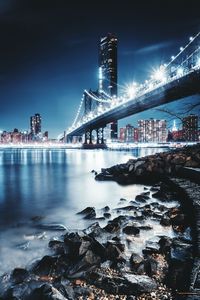 Low angle view of illuminated manhattan bridge over river at night