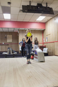 A young woman bowling with friends.