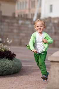 A blond child of european appearance in green clothes happy runs along the senate square in helsinki