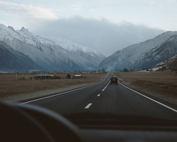 Road amidst mountains seen through car windshield