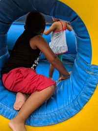 Rear view of siblings playing in bouncy castle