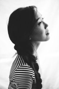 Close-up of woman holding hair over white background