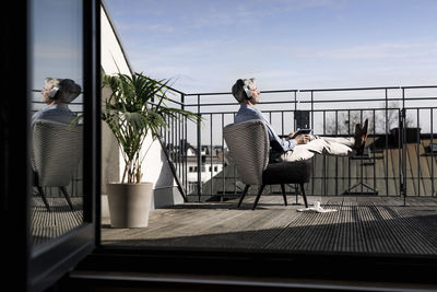 Grey-haired man relaxing in chair on balcony