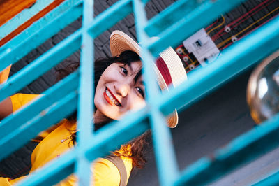 Portrait of smiling young woman seen through fence